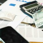 Rozproszone dokumenty finansowe z kalkulatorem, smartfonem i banknotami na biurku